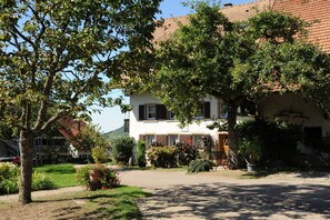 A traditional building with a tiled roof, surrounded by lush greenery and a clear sky. - Apartment 'Talblick, 50 sqm' with Balcony and Wi-Fi (Glottertal)
