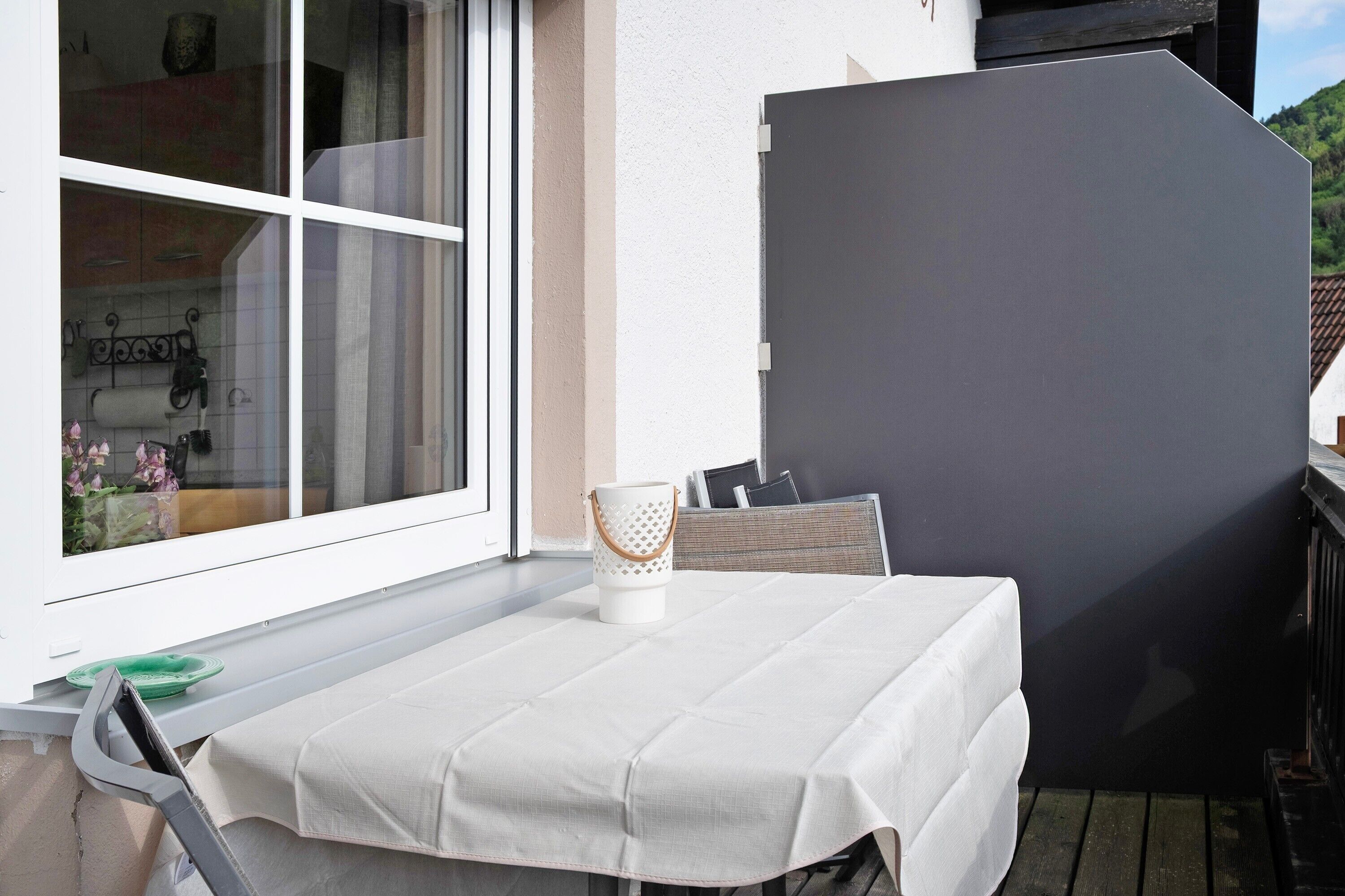A table with a white tablecloth, a white candle holder, and a dark partition.