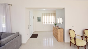 A modern living room with a grey sofa, a wooden cabinet, and two yellow chairs. - Seraina House (94QJ+W7M Pastida, Greece)