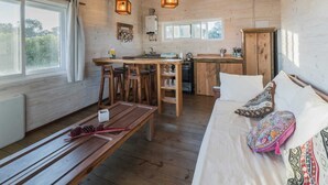 Un chalet confortable avec un intérieur en bois, un coin repas, une cuisine et un lit agrémenté de coussins décoratifs.