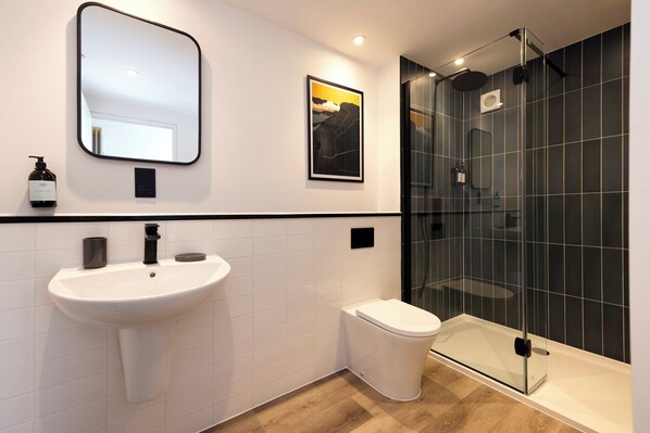 A modern bathroom with a white sink, a toilet, and a glass-enclosed shower. - Abbey Gate Studios (Edinburgh)