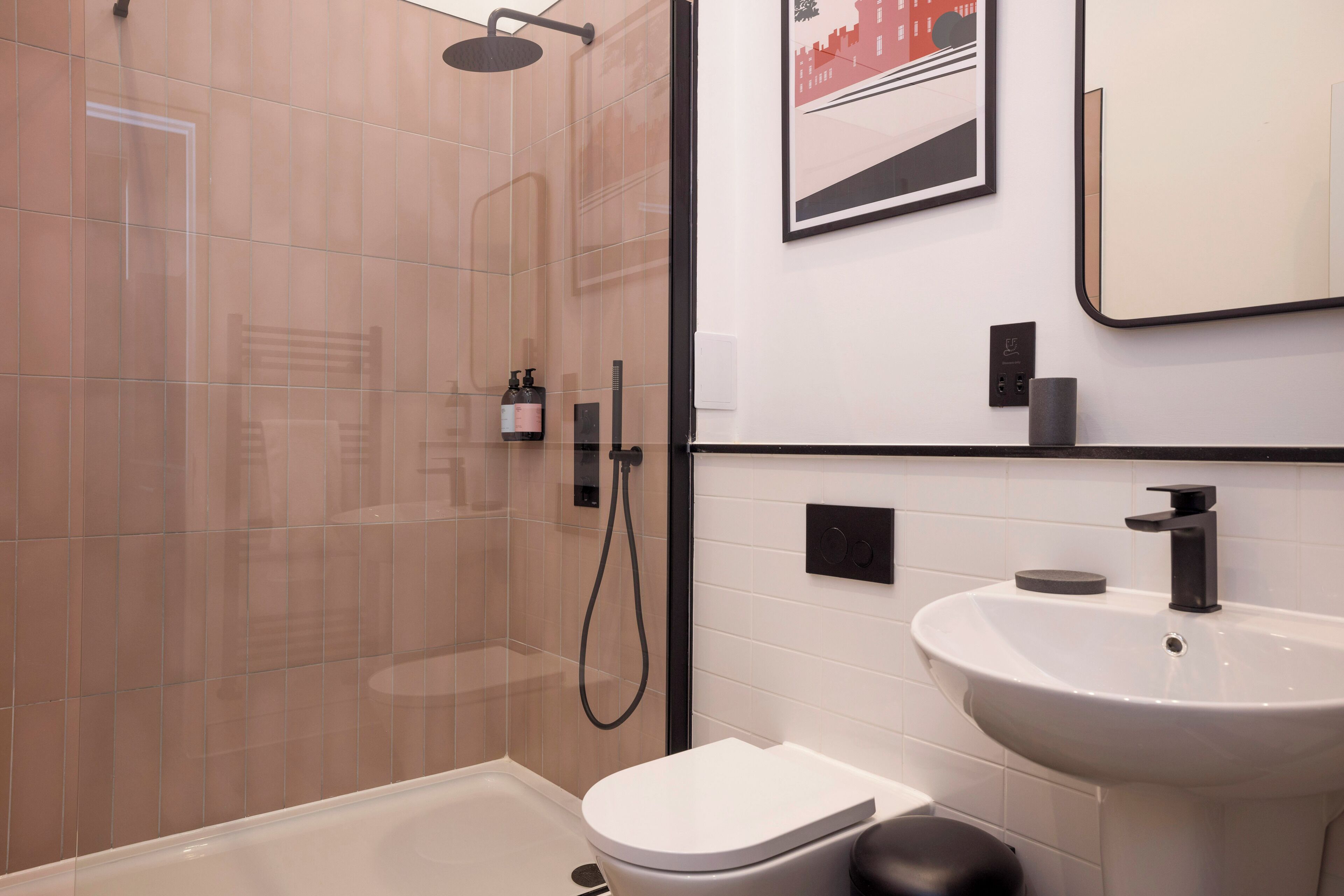 A modern bathroom with a glass-enclosed shower, a white toilet, and a white sink with a black faucet.