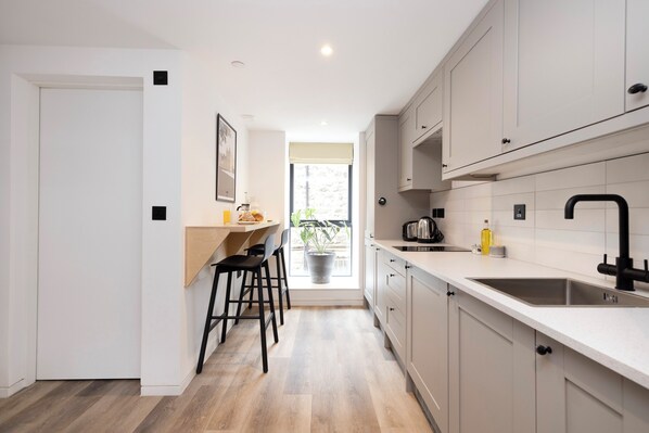 Une cuisine moderne dotée d’un plan de travail en bois, d’un évier et d’une fenêtre donnant sur un jardin.