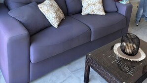 A modern living room with a grey sofa, decorative pillows, a coffee table, wall-mounted clocks, and framed artwork. - Apartment 'Best Sea Views' with Sea View, Wi-Fi and Air Conditioning (Málaga)