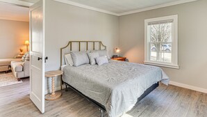 Una camera da letto con un letto, un comodino, una lampada, una finestra e una porta che conduce a un'altra stanza.