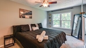 Ein Schlafzimmer mit einem Bett, einem Deckenventilator, einem Fenster und einem Bild an der Wand.