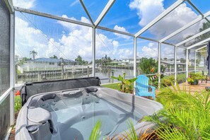 A hot tub inside a glass-enclosed area with a view of a residential neighborhood. - Riverfront Apt w/ Boat Dock in Melbourne Beach! (Melbourne Beach)