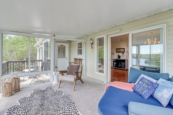 A spacious living room with a large window, a blue sofa, a leopard print rug, and a wooden chair. - Lake-view Gem w/ Game Room in Long Pond! (Long Pond)