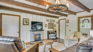 Una sala de estar con chimenea, sofás de cuero, muebles de madera y un televisor.