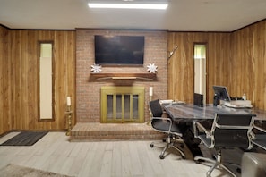 Una sala conferenze con un camino in mattoni, una TV a schermo piatto montata sopra e un pannello di legno a rivestimento.