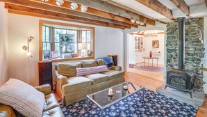 A cozy living room with a wooden ceiling, a stone fireplace, a sofa, and a coffee table. - 9 Mi to Dtwn Hudson: Pet-friendly Home w/ Pool (Craryville)