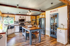 A kitchen with a wooden island, white cabinets, and a blue door labeled "HOME BAKED goods". - Glamping Cabin on Private Pond w/ Deck (Norway)