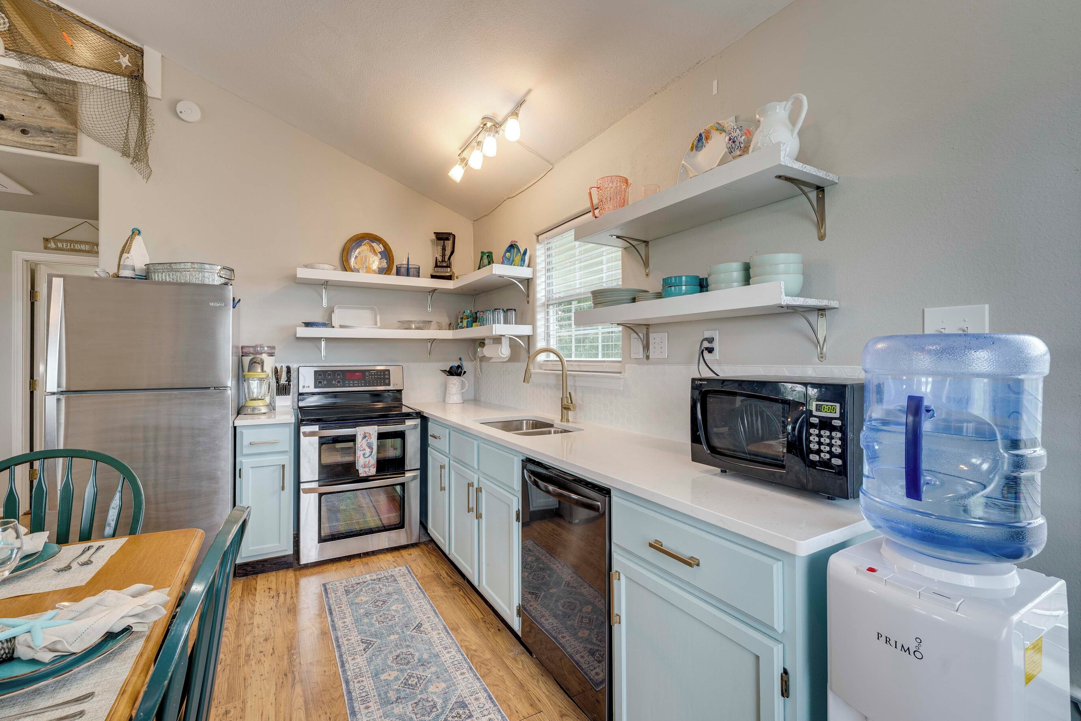 A compact kitchen with a refrigerator, microwave, oven, and water dispenser.
