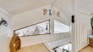 Ein Zimmer mit Holzboden, einem Fenster mit Aussicht, einem Regal mit einem Fisch und einem Schild, auf dem 'FISH' steht.