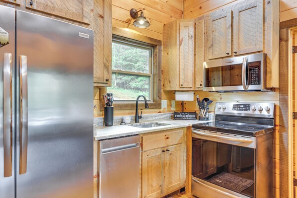 A compact kitchen with a stainless steel refrigerator, a microwave, and an oven. - Riverside Retreat - Tranquility and Fun (McCaysville)