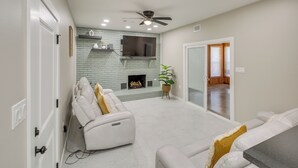 Ein modernes Wohnzimmer mit Kamin, weißen Sofas und Deckenventilator.