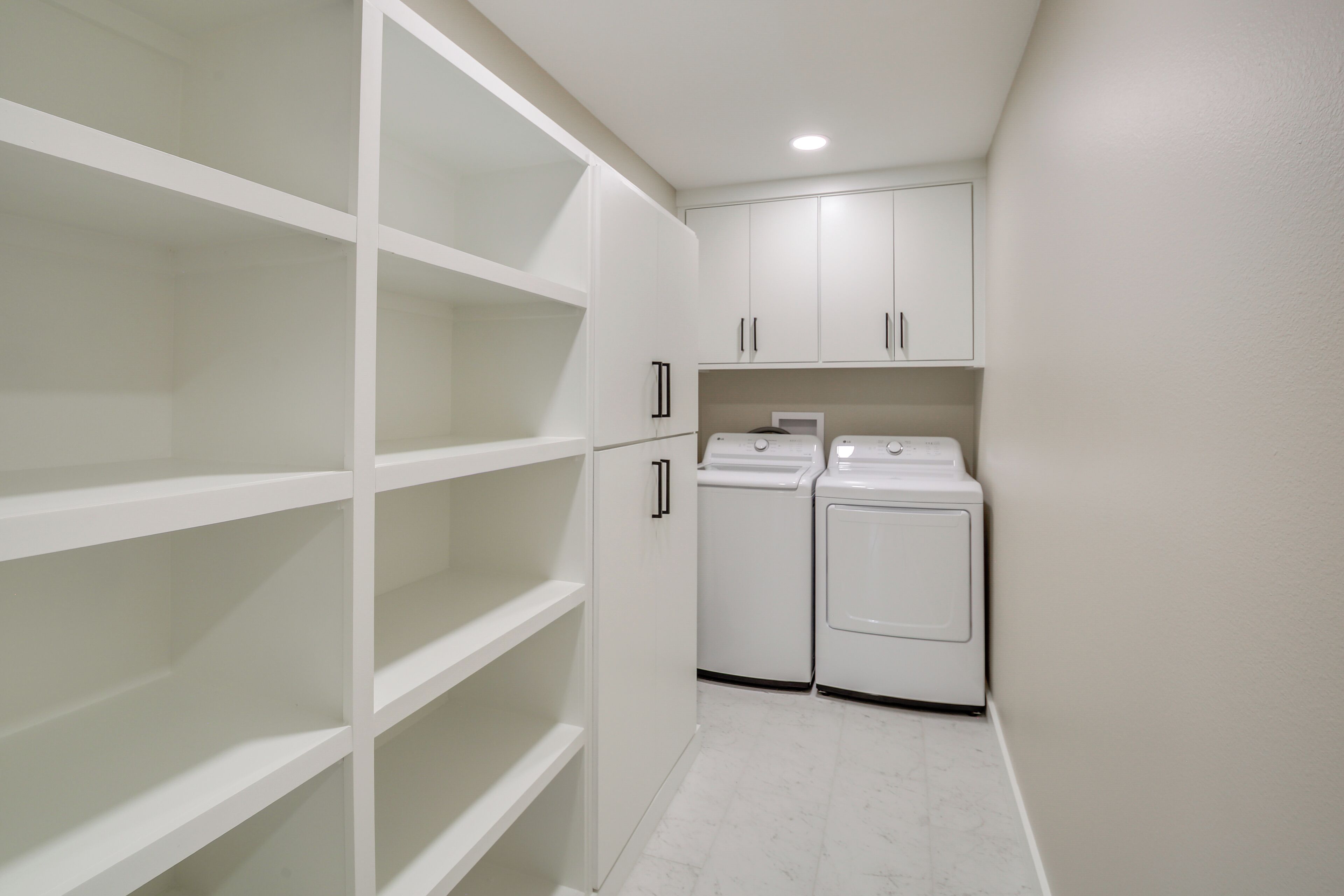 A laundry room with white cabinets and two washing machines.
