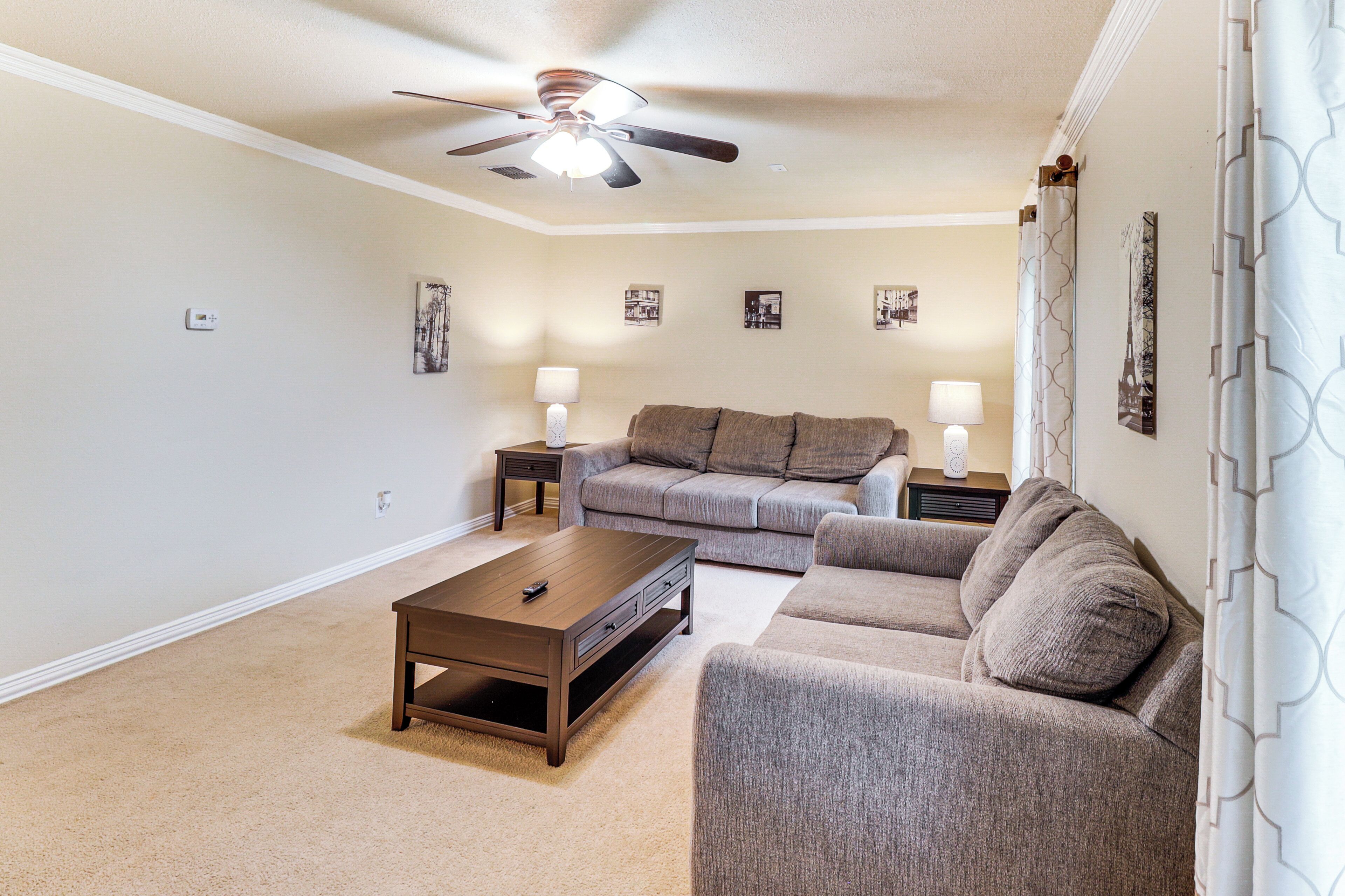 A living room with a ceiling fan, two couches, a coffee table, and two lamps.