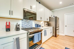 A modern kitchen with white cabinets, a stainless steel range hood, and a built-in oven. - 11 Mi to Dtwn: Luxe Atlanta Retreat w/ Deck & Yard (Atlanta)