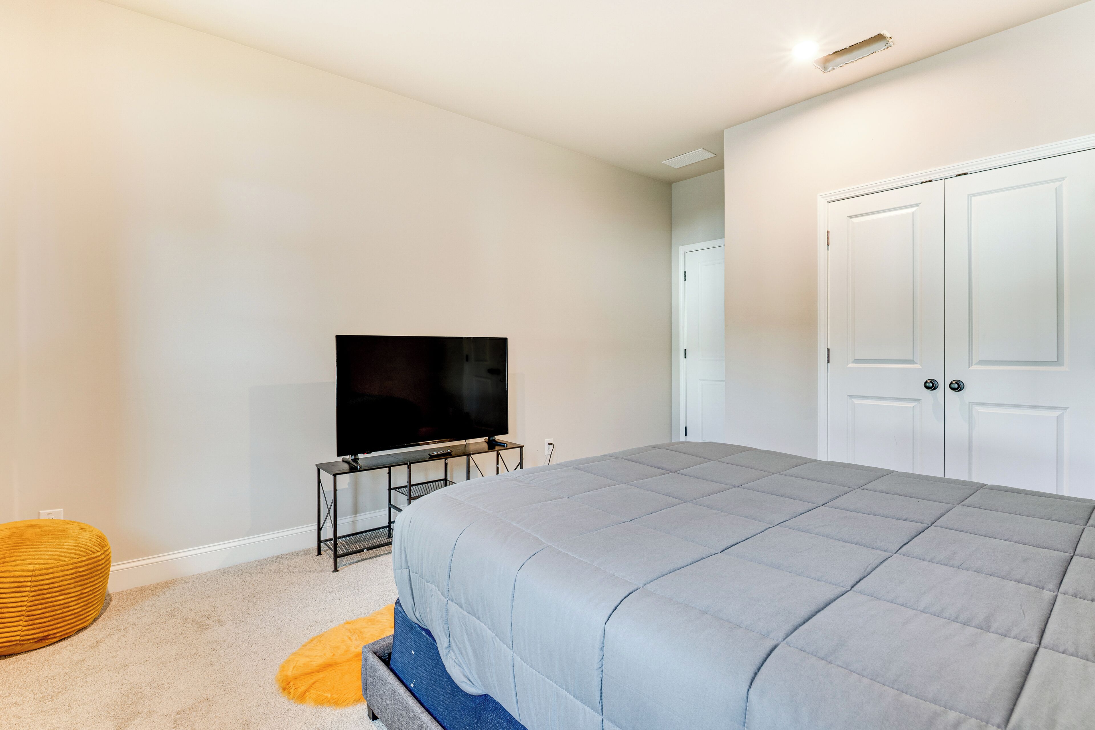Une chambre à coucher avec un lit, un téléviseur posé sur un meuble, une armoire et une porte.