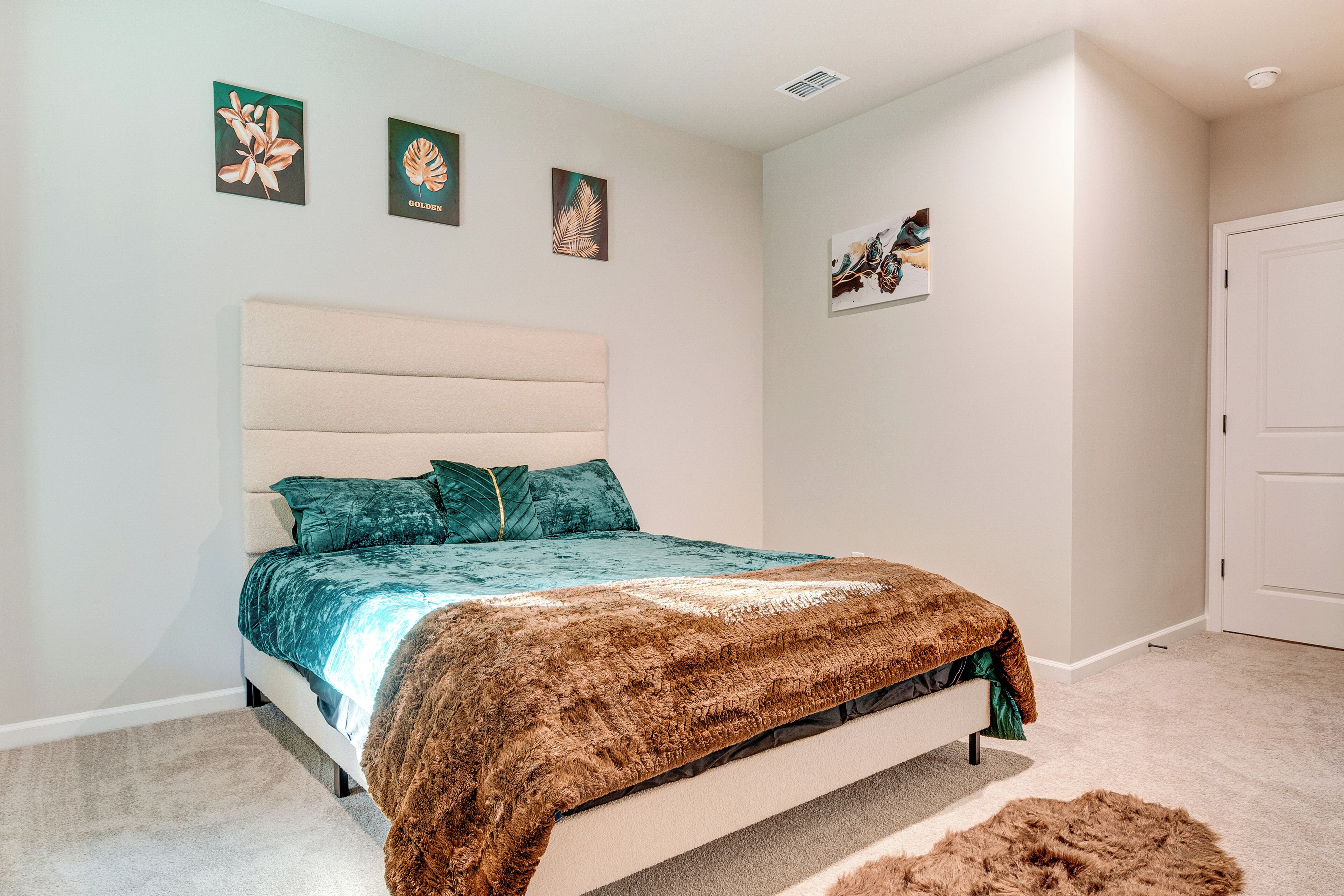 A bedroom with a bed, a headboard, and a door.