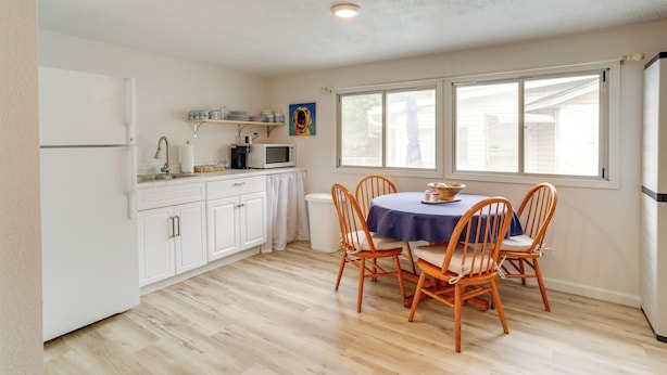 A compact kitchen with white cabinets, a microwave, and a dining table with four wooden chairs. - Walk to Norfork Lake: Guest House in Henderson (Henderson)