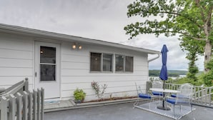 A white building with a porch, a small garden, and a blue umbrella. - Walk to Norfork Lake: Guest House in Henderson (Henderson)