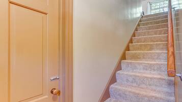 A carpeted staircase with a wooden handrail and a door with a brass doorknob.