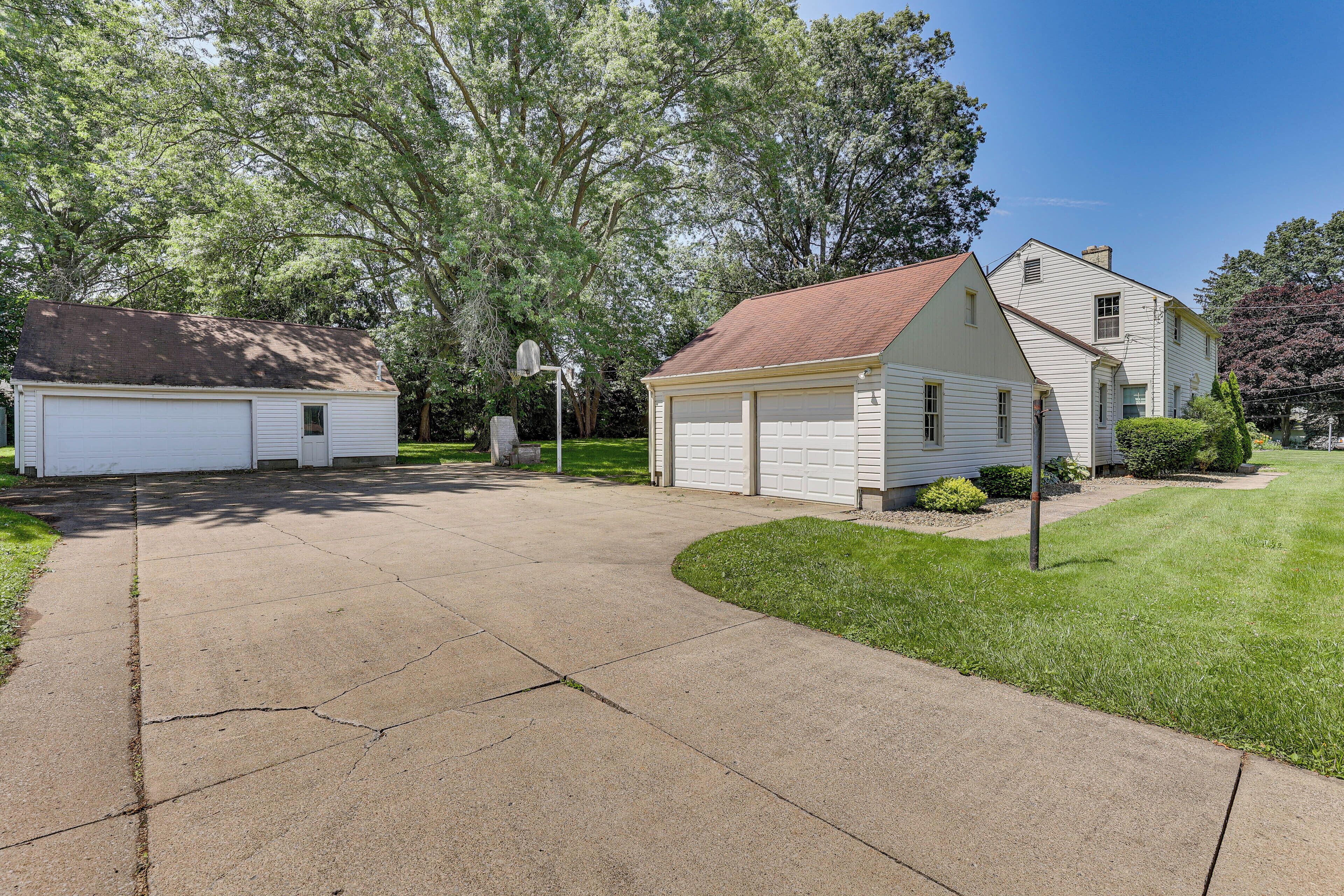 A residential driveway leading to a house with a garage and a shed.