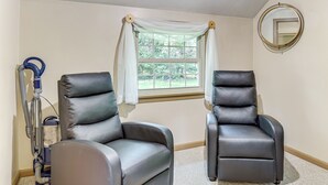 A room with two leather recliners, a window with white curtains, a vacuum cleaner, and a round mirror on the wall. - 1 Mi to Dtwn Salem: Apt w/ Garage Access! (Salem)