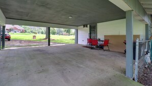 A covered patio area with a concrete floor, a table with chairs, and a view of a grassy yard and a building in the background. - 16 Mi to Dtwn Jackson: Quiet Southern Escape (Terry)