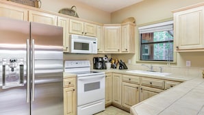 A kitchen with stainless steel appliances, a microwave, a stove, and wooden cabinets. - Pickwick Lake Cabin w/ Private Marina Access (Iuka)