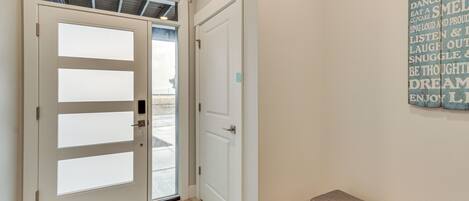 Un pasillo con una puerta que da al exterior, un banco y una pared con mensajes inspiradores.