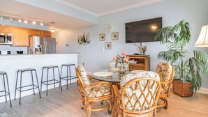 Une cuisine moderne avec un coin bar, des meubles en osier et un téléviseur à écran plat.