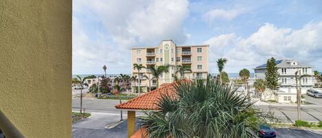 A multi-story hotel with a tiled roof, a central courtyard, and a view of the ocean.
