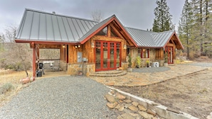 A log cabin with a stone foundation, a metal roof, and a front porch with outdoor seating. - Peaceful Shasta Cascade Getaway on 15-acre Ranch! (Weaverville)