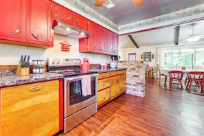 Une cuisine avec des meubles de couleur rouge, un four en acier inoxydable et un plancher en bois.