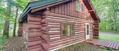 A log cabin with a wooden exterior, a front porch, and a chimney.