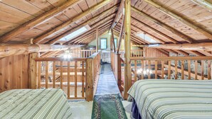 A wooden cabin with a loft bedroom, a staircase leading to the upper floor, and a view of the surrounding forest. - Authentic Log Cabin w/ Private Pond in Glidden (Glidden)