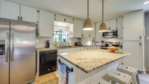 A modern kitchen with stainless steel appliances, white cabinetry, and a granite countertop. - Fire Pit + Ping-pong: Home on Guadalupe River! (Seguin)
