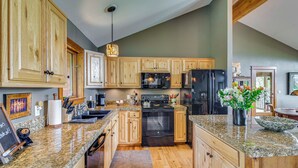 A kitchen with wooden cabinets, granite countertops, a black oven, a microwave, and a refrigerator. - Private 5 Acres w/ Mtn Views: Park County Cabin! (Jefferson)