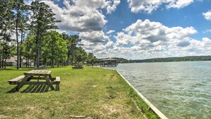 A lakeside park with picnic tables and a dock extending into the water.