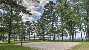 A park with a sandy area, trees, and a body of water in the background.