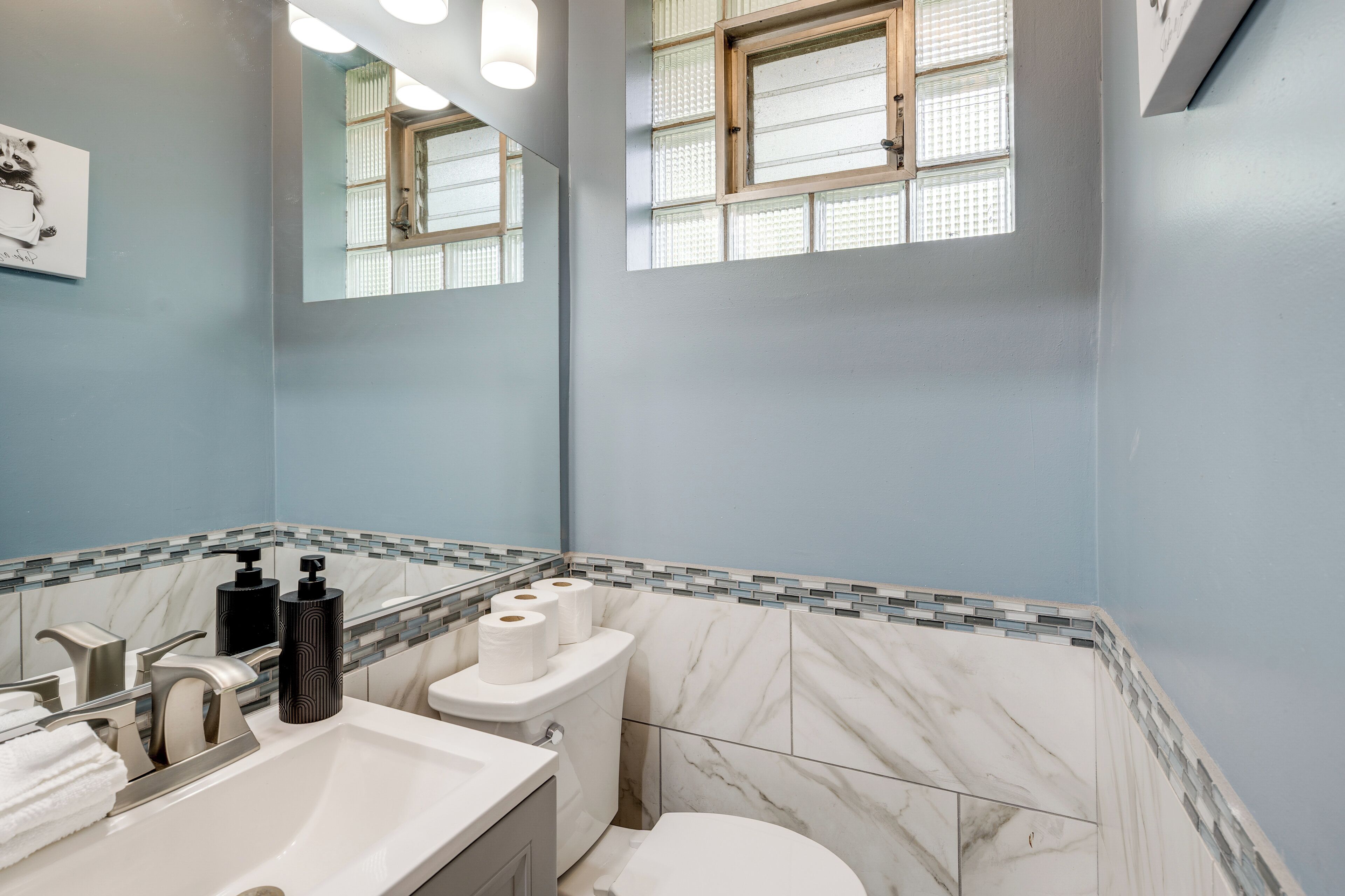 A bathroom with a marble sink, a toilet, and a mirror.