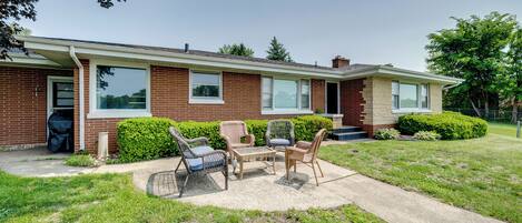 A two-story brick house with a patio area featuring outdoor furniture.