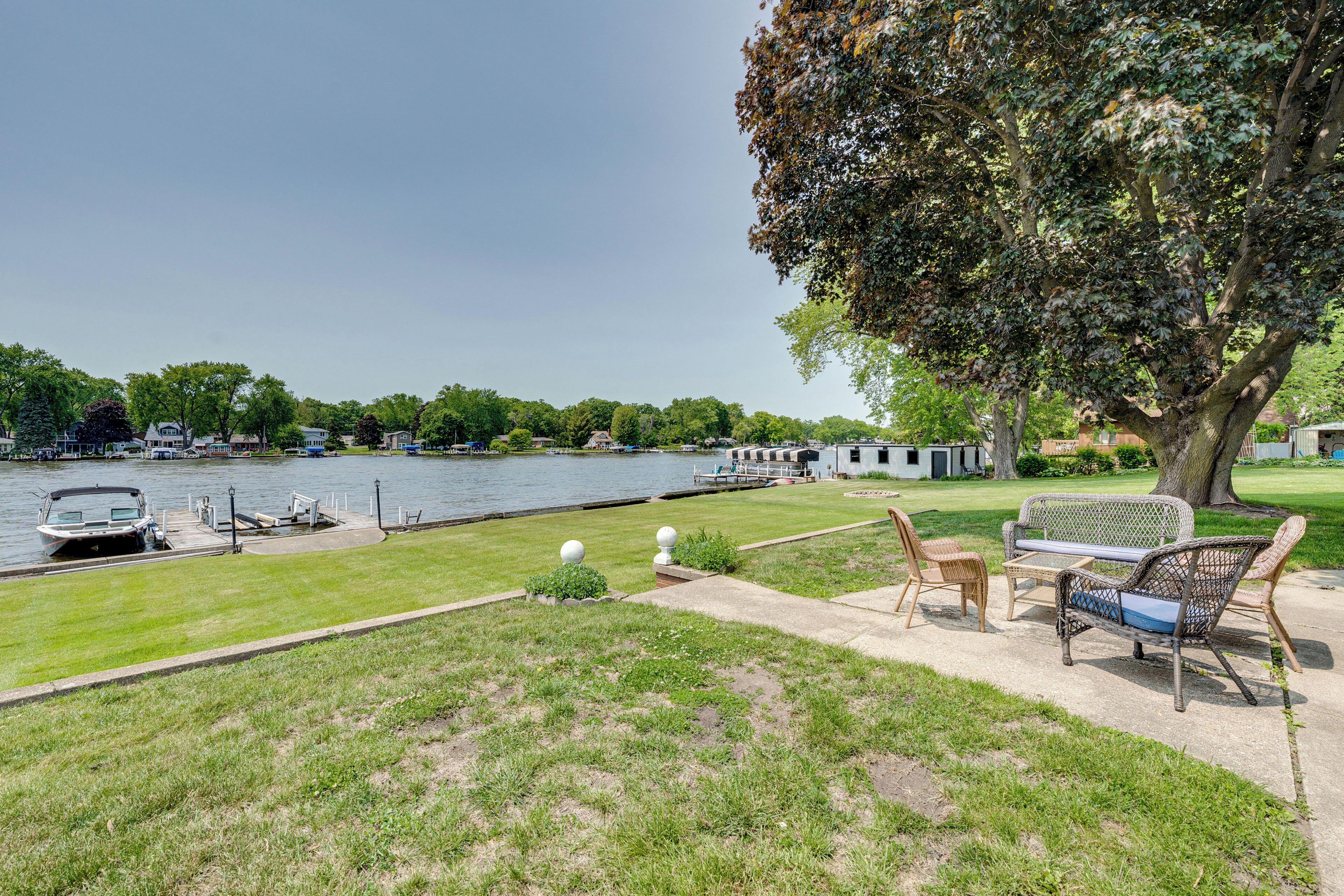 Une propriété au bord du lac, dotée d’un quai, d’un bateau, d’une table de pique-nique et d’un grand arbre.