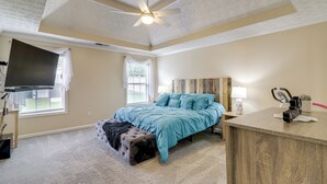 Ein Schlafzimmer mit Bett, Schreibtisch, Deckenventilator und Fernseher.