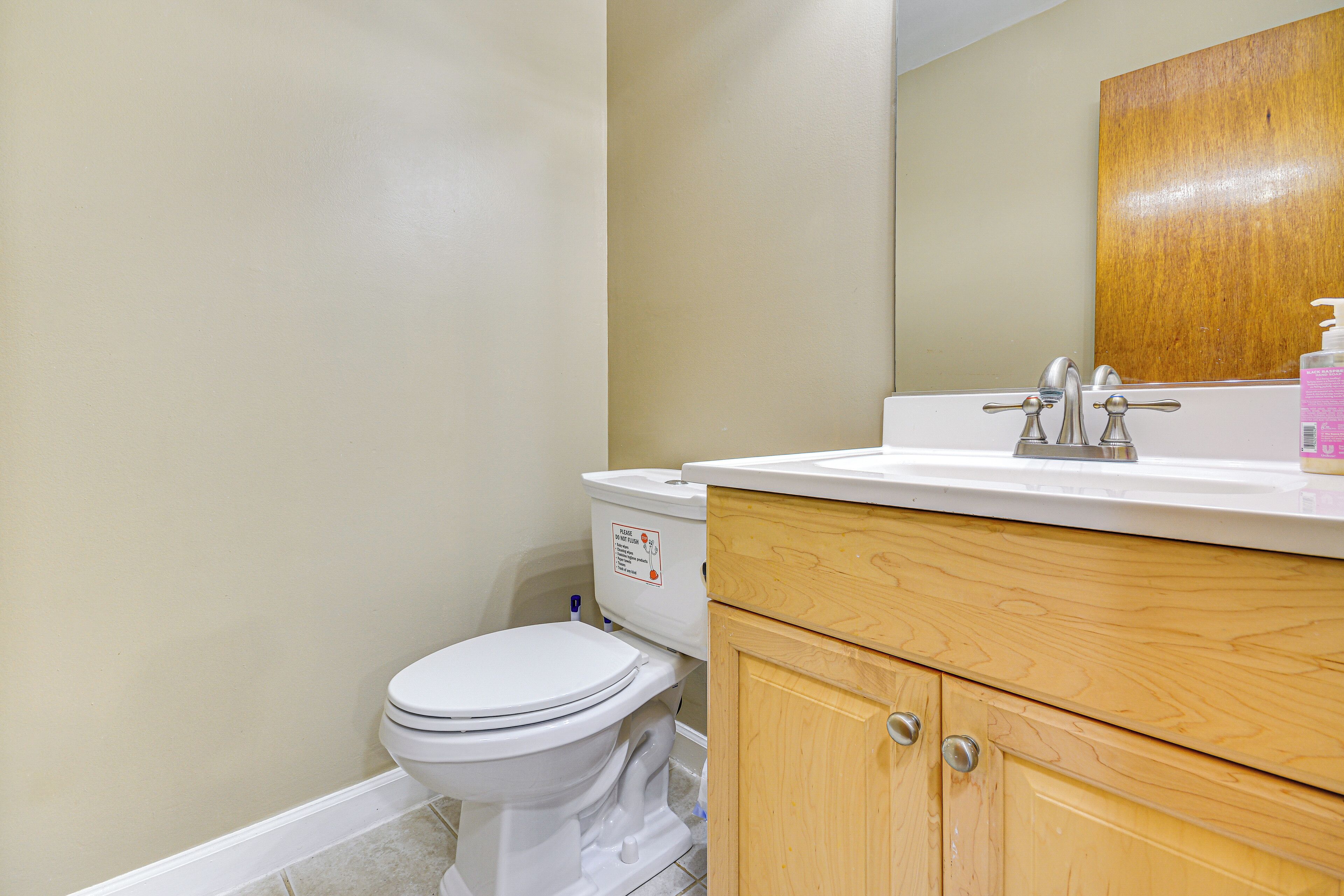 A bathroom with a toilet, a wooden vanity, and a mirror.