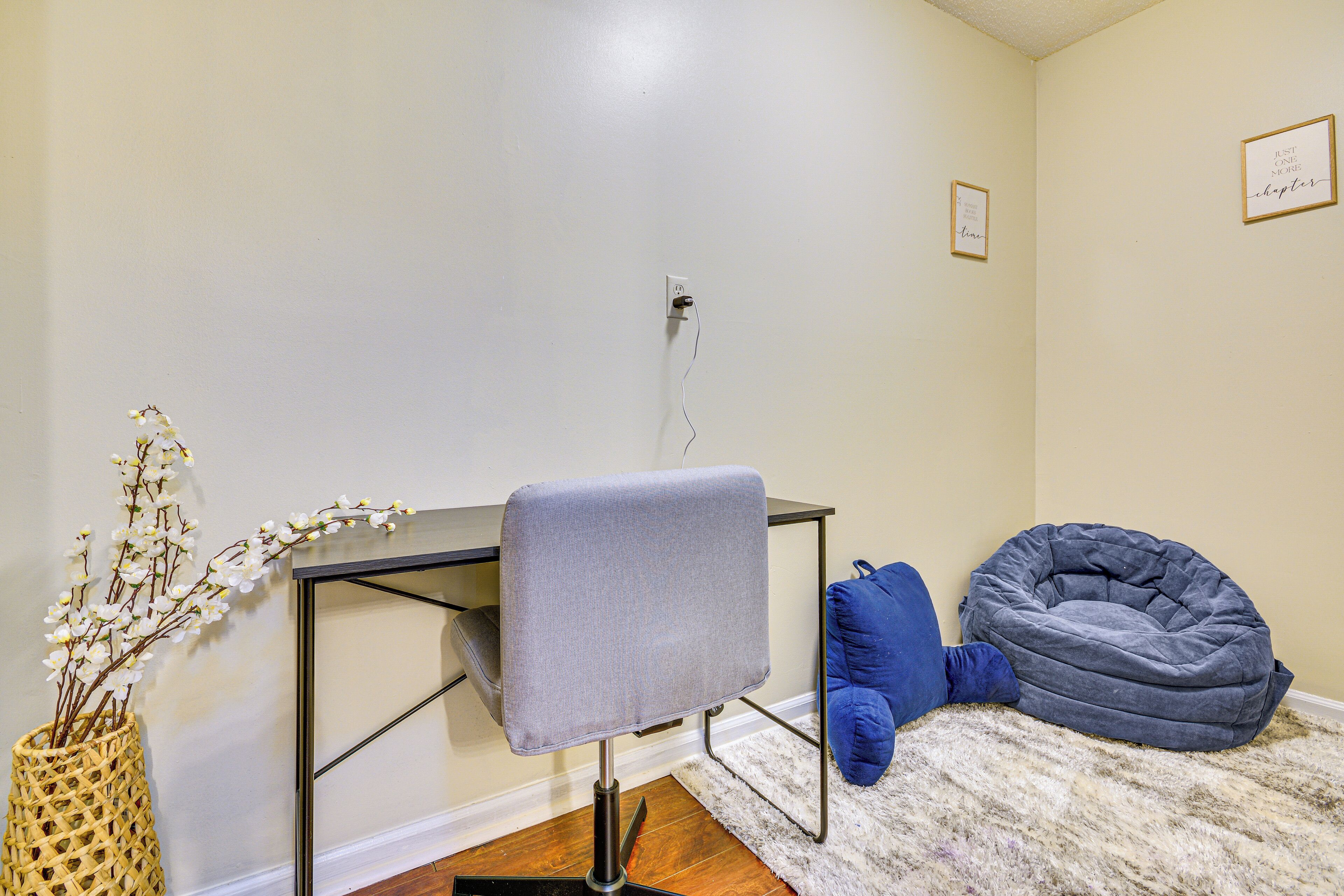 Ein Zimmer mit Schreibtisch, Stuhl, Sitzsack und einer dekorativen Vase.