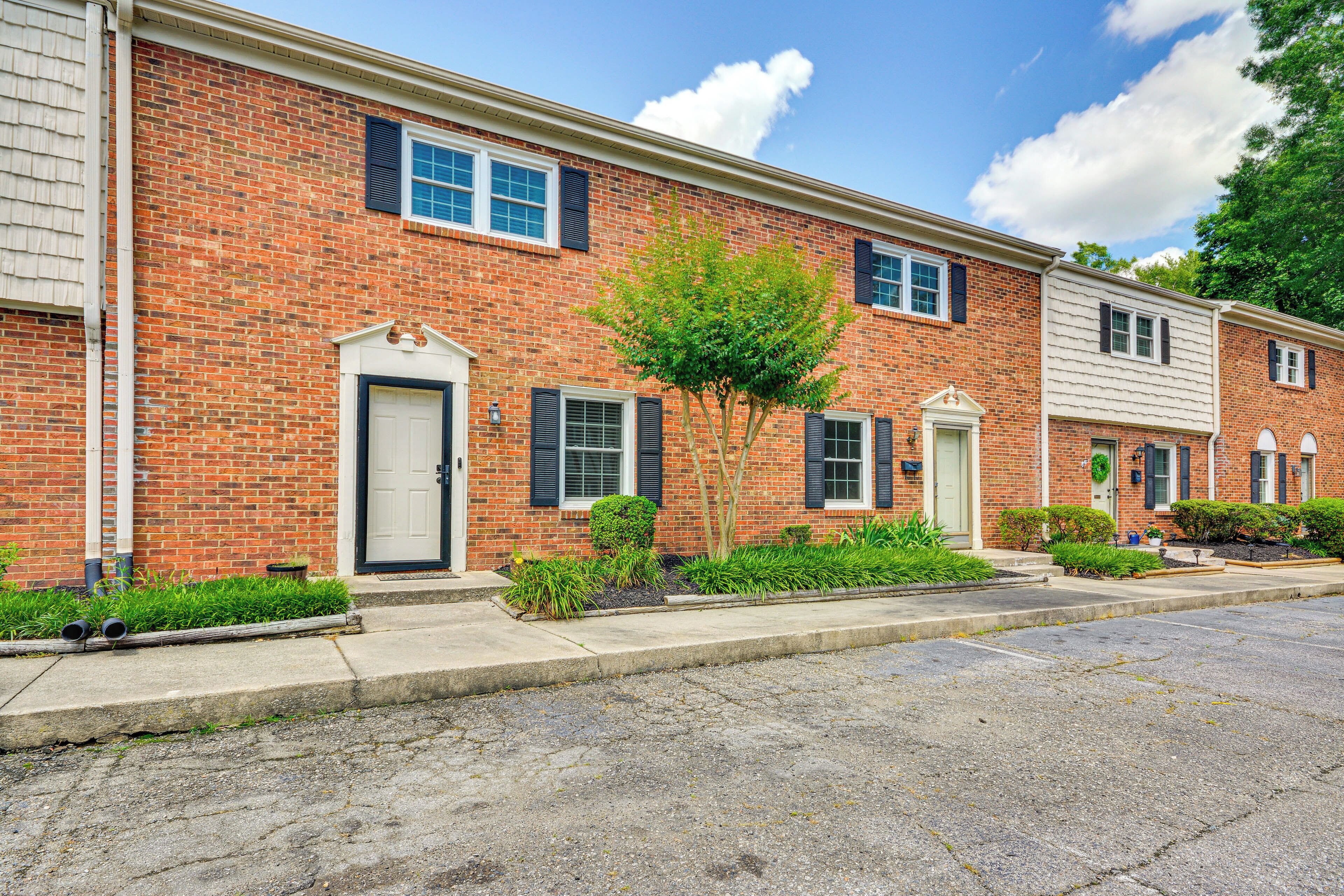 A row of brick townhouses with front doors, small front yards, and a clear sky.